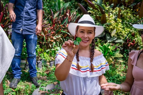 A happy participant gets to know the coffee plant on a Colombian coffee farm – part of one of the best day trips from Medellín.