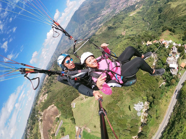 A paraglider soars high above the city, a thrilling perspective from one of the best day trips from Medellin, Colombia.