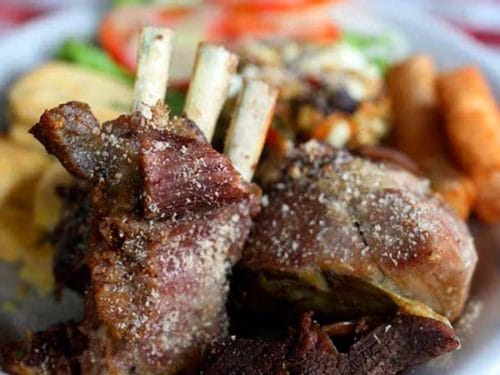 A close-up of tender, slow-roasted goat ribs, showing the delicious result of the traditional Cabro Santandereano dish.