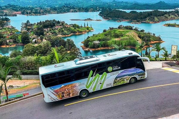 A comfortable tour bus parked by the stunning Guatapé reservoir, part of a seamless all-inclusive day trip from Medellin, Colombia.