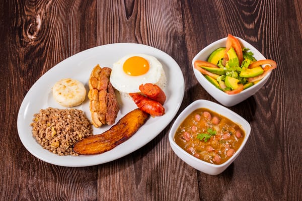 A hearty platter showcasing Colombian breakfast foods, with a fried egg, beans, meat, and plantain, typical of the Andean region.