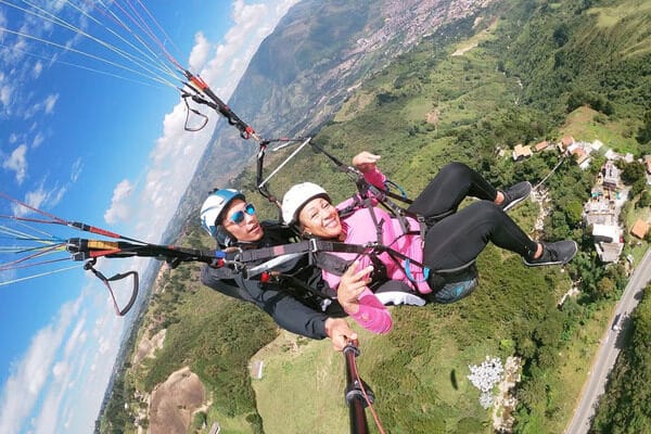 A paraglider soars high above the city, a thrilling perspective from one of the best day trips from Medellin, Colombia.