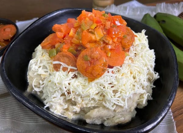 A plate of Cayeye, a traditional Colombian breakfast from the Caribbean coast made from mashed green bananas and topped with cheese and a savory sauce.