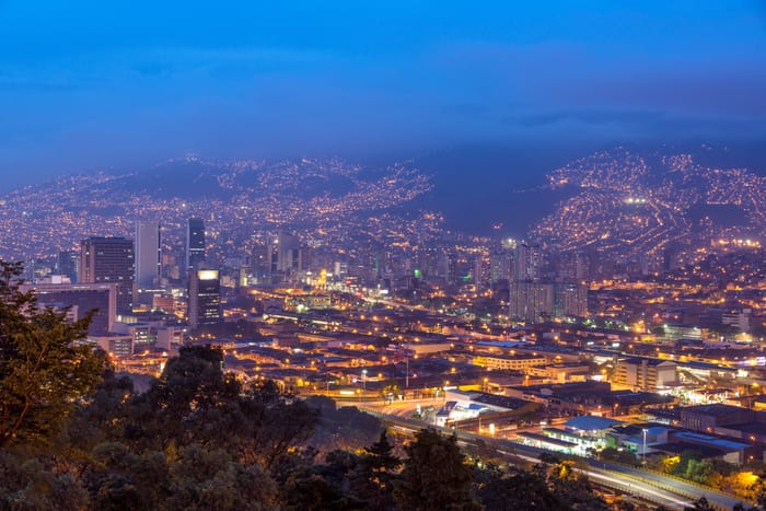A stunning panoramic view of Medellín's city lights at night from a mountain viewpoint, a sight that inspires many to ask, 'is safe Medellin to travel to?'