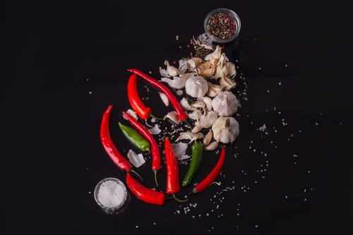 Fresh red and green chili peppers with garlic and salt, the core ingredients for the Colombian ají sauce that lets you decide for yourself 'is Colombian food spicy?'.