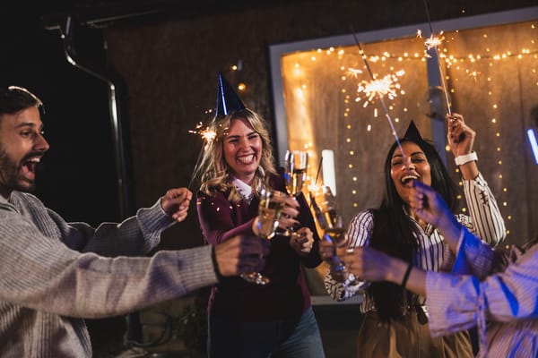 Friends celebrating with sparklers and drinks, capturing the joyful atmosphere of the many parties where Colombian New Year traditions are practiced.