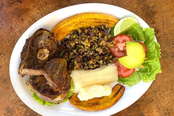 The complete plate of Cabro Santandereano, featuring tender goat meat served with traditional pepitoria rice, fried plantains, and yucca.