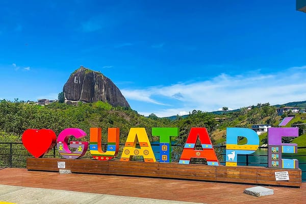 The famous Guatapé sign with the iconic Guatapé Rock El Peñol in the background, a perfect photo stop on a day trip from Medellin.