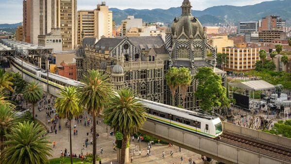 The Medellin metro passing the Rafael Uribe Palace of Culture, showcasing the vibrant downtown area found on any detailed medellin neighborhood map.