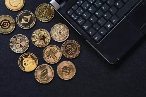 Collection of various cryptocurrency coins next to a keyboard, representing the diverse digital assets available in crypto Medellin.
