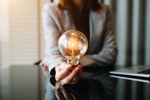 Woman holding a glowing light bulb, symbolizing innovation and ideas in the crypto Medellin scene.